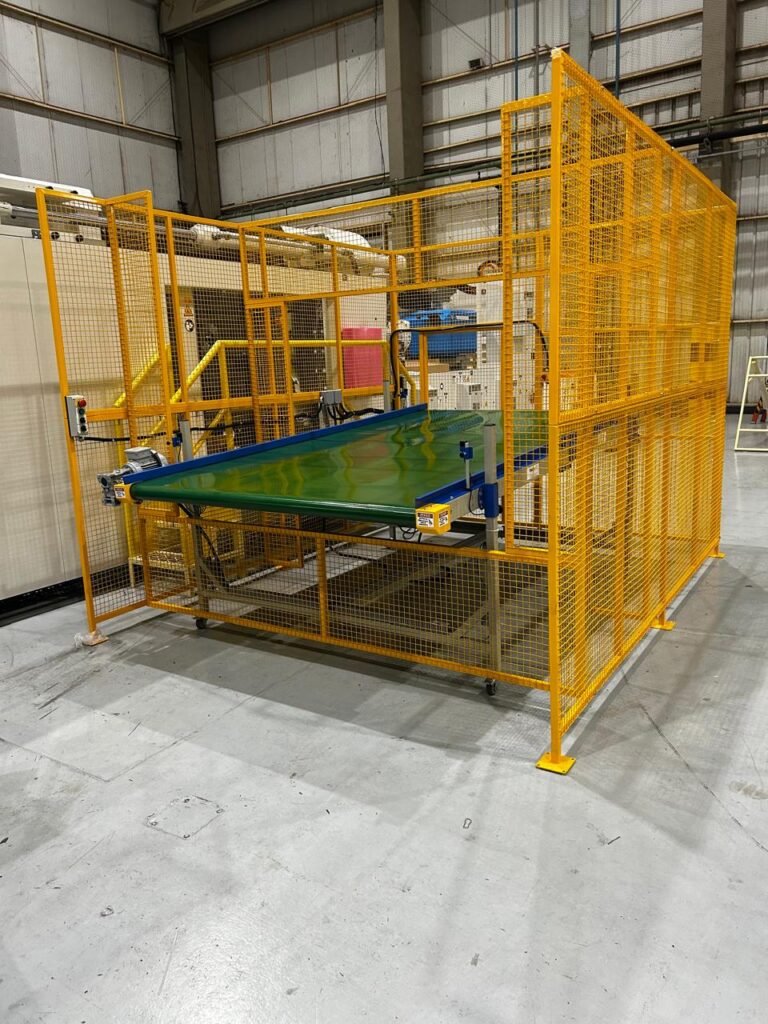 Esteira transportadora horizontal com gaiola de proteção amarela e sensores de segurança para área de robô em conformidade com a NR-12.